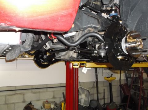 1999 Mercury Grand Marquis - The front suspension of a vehicle is shown on a lift, with focus on the brake assembly and steering components.