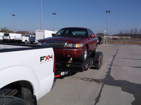 1999 Mercury Grand Marquis - A red 1999 Mercury Grand Marquis is loaded onto a trailer, ready for transport.