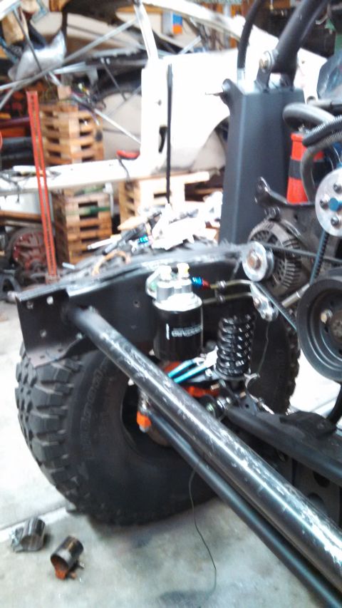 1967 Ford F-250 - Close-up of a custom vehicle's chassis, showing suspension and engine parts, with a large tire on the left.
