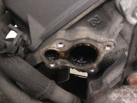 1994 Ford Bronco - This image shows a close-up of a dirty engine component with significant carbon buildup, obscuring internal details.