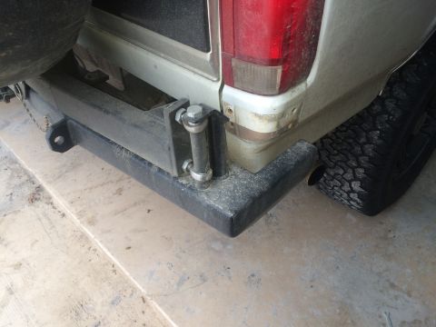 1996 Ford Bronco - The rear bumper and tire of a light-colored SUV are visible, with a spare tire mounted externally.