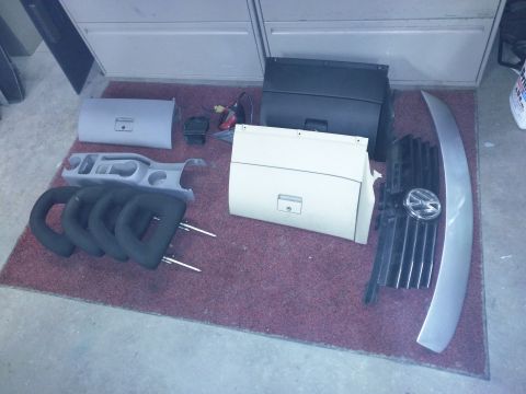 2002 Volkswagen Jetta - Interior and exterior parts, including a grille with the Volkswagen emblem, are laid out on a rug.