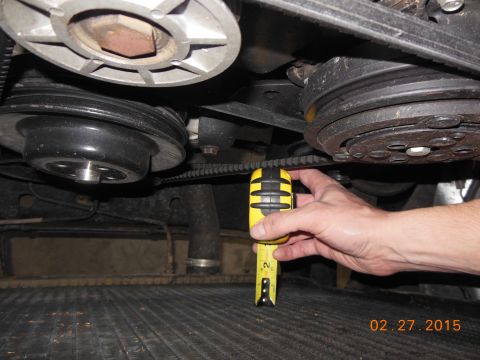 1979 Ford F-150 - Close-up view of engine components, including a serpentine belt and pulleys, with a tape measure for scale.