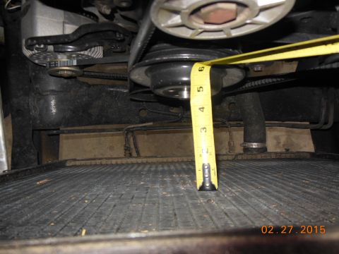1979 Ford F-150 - Close-up view of an engine pulley being measured with a tape measure, positioned above a vehicle's radiator.