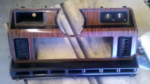 1982 Ford Bronco - Dashboard trim panel with faux woodgrain finish and air vents.