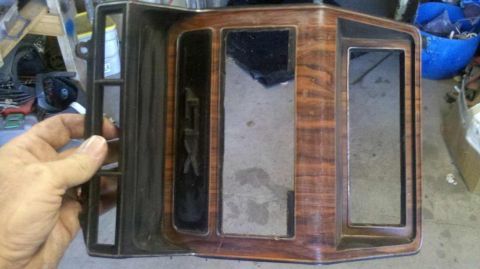1982 Ford Bronco - A hand holds a dashboard trim piece with faux wood grain and a prominent 'GTX' emblem.