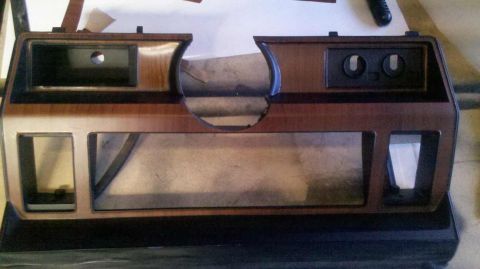 1982 Ford Bronco - This dashboard trim piece features a wood-grain finish and several cutouts for vehicle components.