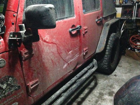 1979 Ford Bronco - This red Jeep Wrangler is covered in dirt and has custom side steps, suggesting it's used for off-roading.