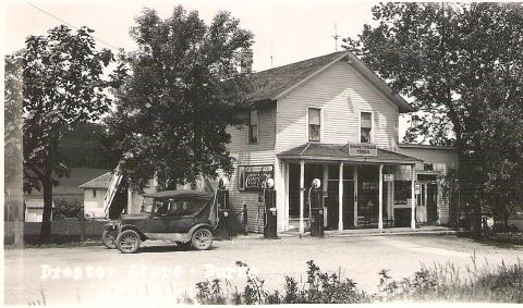 1909 Ford Model T - A vintage sedan is parked at a rural gas station with visible Coca-Cola signage.
