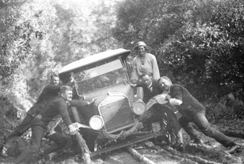 1909 Ford Model T - A group of people struggle to free a 1909 Ford Model T from a muddy ditch.
