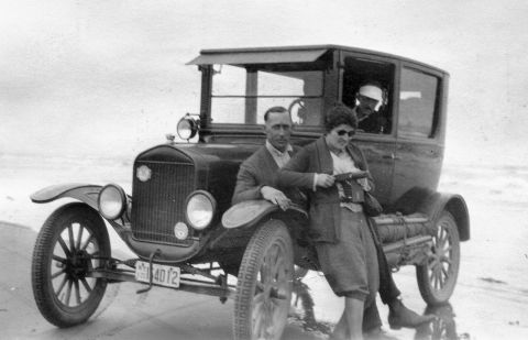 1909 Ford Model T - A 1909 Ford Model T sits on the sand with two passengers, one holding a camera.