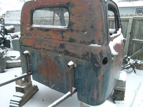 1986 Ford Bronco - This heavily rusted truck cab sits outdoors in the snow, showing significant wear and tear.