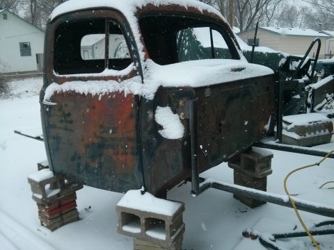 1986 Ford Bronco - This is a rusted truck cab sitting on cinder blocks in the snow.