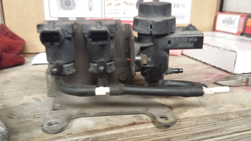 Ford vacuum solenoid assembly with hoses and bracket, marked F0TE-A1A, on a workbench