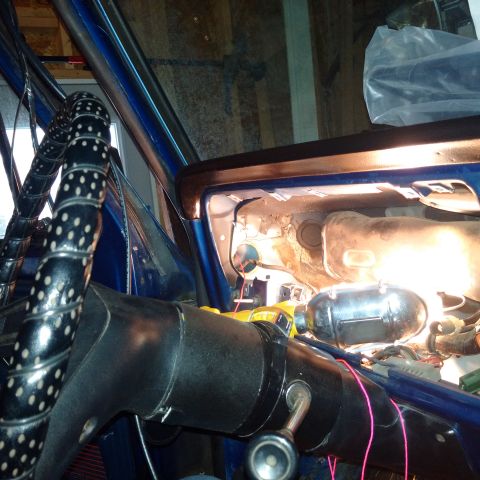 1978 Ford Bronco - The interior of a blue vehicle shows exposed dashboard components and wiring, with a black steering wheel.