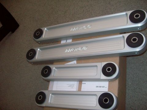 2004 Ford Crown Victoria - Four silver control arms with black bushings are laid out on a cardboard box.
