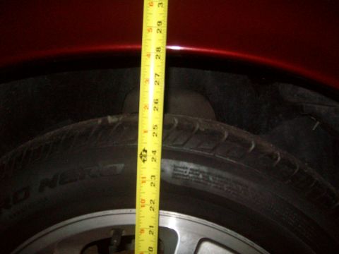 2004 Ford Crown Victoria - Measuring the suspension height of a vehicle with a tape measure against the tire and fender.