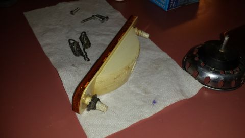 1976 Ford Ranchero - A disassembled car part, possibly a marker light, lies on a cloth with screws and springs.
