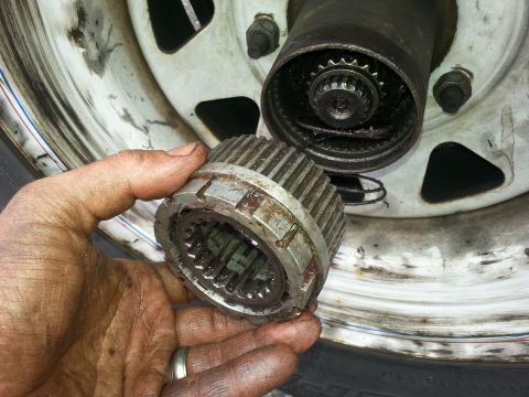 1981 Ford Bronco - Close-up of a manual locking hub being held, with the wheel and hub assembly visible.