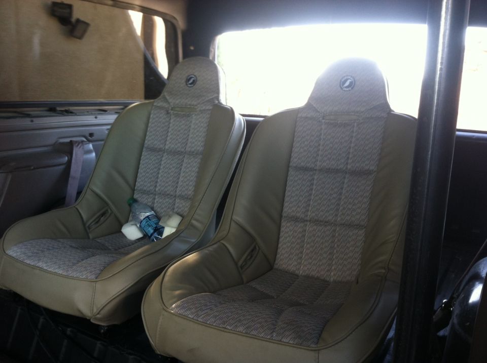 Two bucket seats inside a vehicle, with a water bottle on the left seat