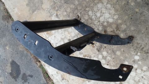 Black metal automotive part with mounting holes on concrete