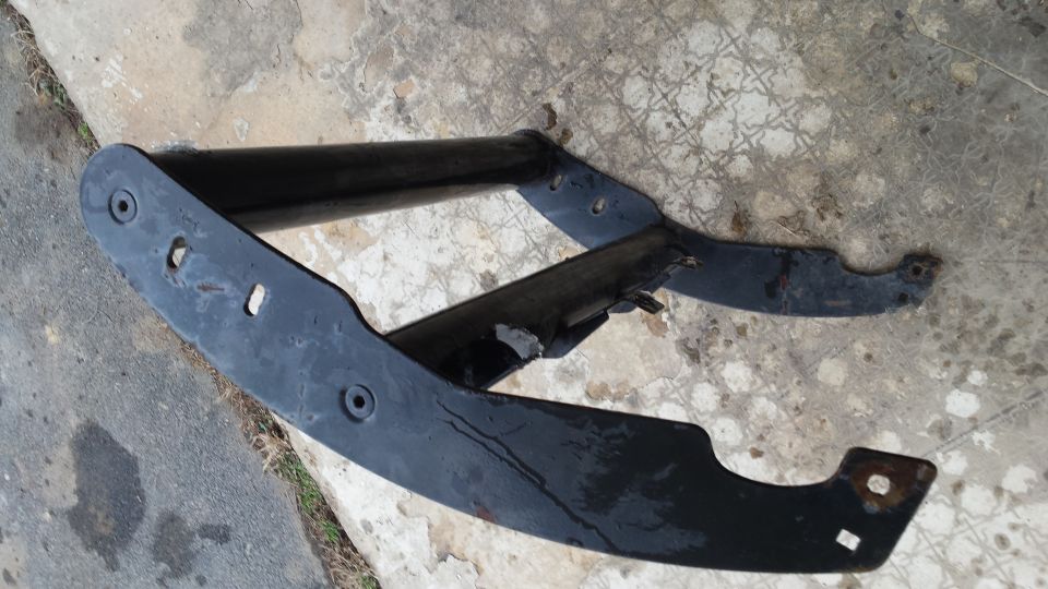 Black metal automotive part with mounting holes on concrete