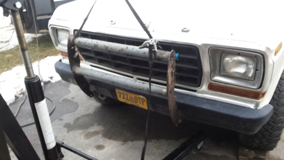 Front of a 1979 Ford Bronco being lifted by a hoist, showing grille and headlights