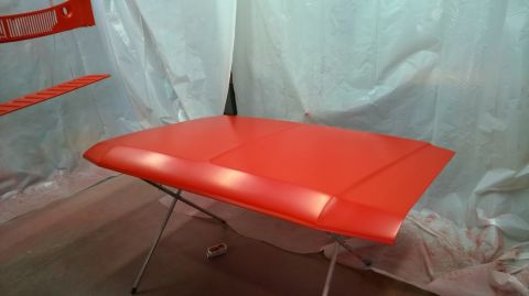 1983 Ford Bronco - An orange hood is shown on a stand, likely in a spray booth for painting.