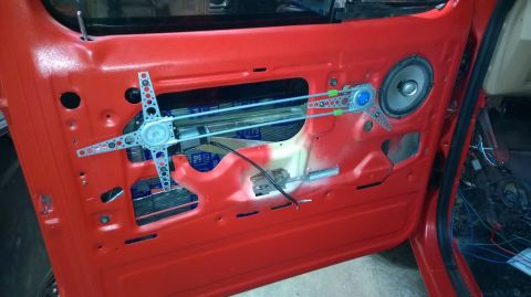 1983 Ford Bronco - Interior view of a red vehicle door panel showing the window regulator and speaker assembly.