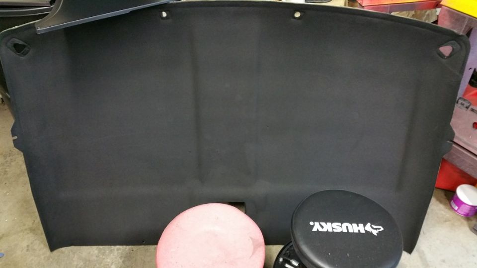 Black headliner with mounting holes, sitting on a pink stool and a Husky stool
