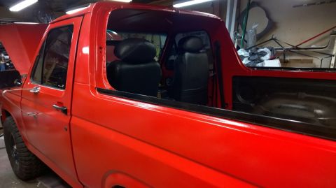 1983 Ford Bronco - A red Ford Bronco is shown from the side with its hood up and black interior visible.