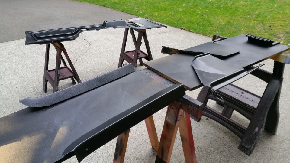 Black interior trim pieces drying on sawhorses, with SuperMotors logo visible