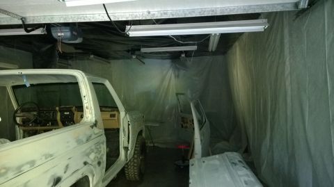 1983 Ford Bronco - Two vehicles, likely Ford F-Series trucks, are in a garage being worked on, with parts removed.
