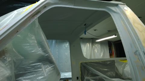 1983 Ford Bronco - The interior of a vehicle is covered in plastic sheeting and primer, suggesting it is undergoing repairs or restoration.