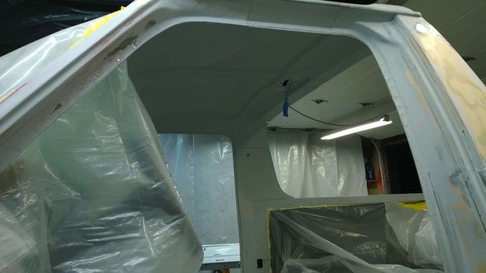 White vehicle interior with plastic sheeting, primer, and a fluorescent light