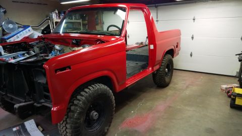 1983 Ford Bronco - This red Ford Bronco is undergoing restoration in a garage, with its doors and hood removed.