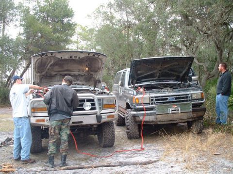 1992 Ford Bronco - Two Ford trucks are having their batteries jumped with jumper cables in an outdoor setting.