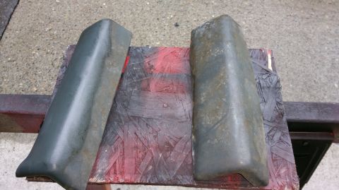 1983 Ford Bronco - Two automotive bumper end caps are shown, resting on a surface with red spray paint markings.
