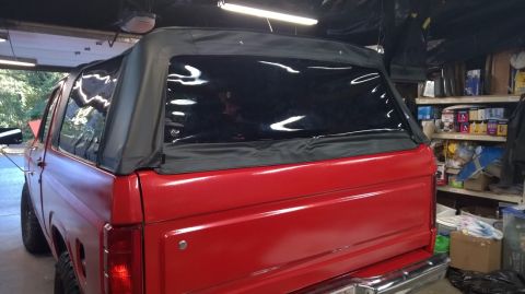 1983 Ford Bronco - Rear view of a red SUV with a black soft top, showing its body style.