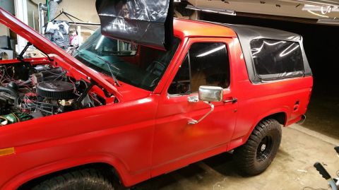 1983 Ford Bronco - This 1983 Ford Bronco is shown with its hood open, revealing the engine bay and a black soft top.