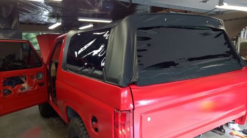 1983 Ford Bronco - Red 1983 Ford Bronco with soft top, interior visible through clear windows.