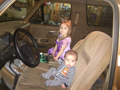 1991 Ford Bronco - Two children sit inside the cabin of a 1991 Ford Bronco, with the dashboard and steering wheel visible.