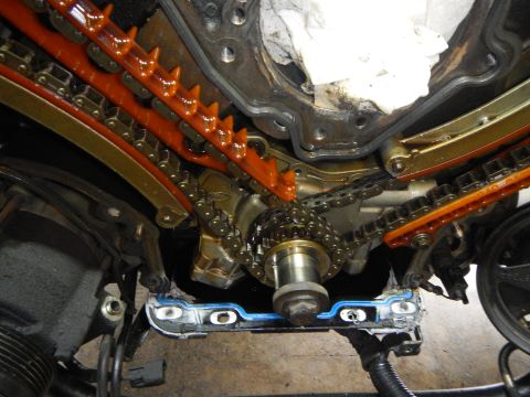 2002 Ford Mustang - Disassembled engine timing chain assembly with visible sprockets and guides.