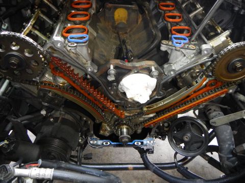 2002 Ford Mustang - Close-up view of an engine's timing chain and associated components, with visible orange and blue gaskets.