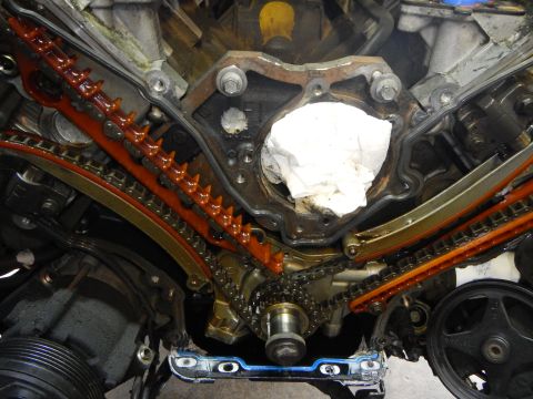 2002 Ford Mustang - Disassembled engine timing chain and guide system with white cloth in cavity.