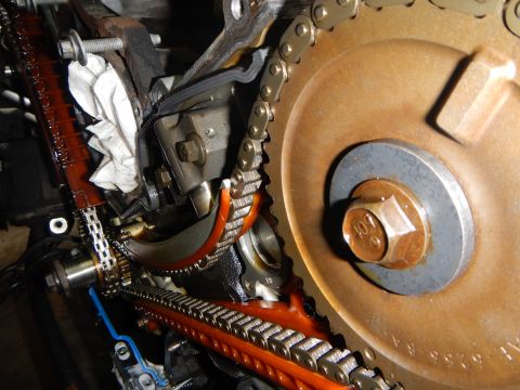 2002 Ford Mustang - Close-up view of engine timing components, including chains and gears, with visible orange plastic guides.