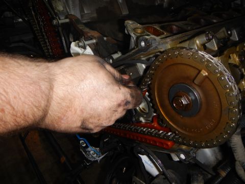 2002 Ford Mustang - Mechanic's hand working on engine timing chain and gears, with SuperMotors.net watermark visible.