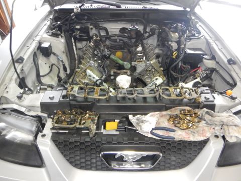 2002 Ford Mustang - The engine of a 2002 Ford Mustang is partially disassembled, with various components laid out on the engine bay and a cloth.
