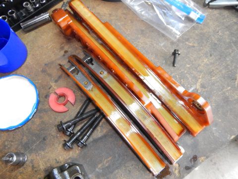 2002 Ford Mustang - Timing chain guides and bolts are shown on a workbench, likely for a vehicle repair.