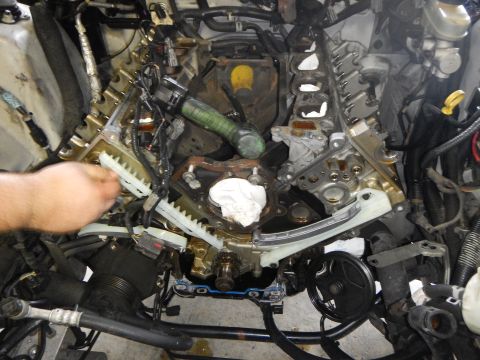 2002 Ford Mustang - Mechanic's hands are visible as they work on the exposed timing chain system of a vehicle engine.